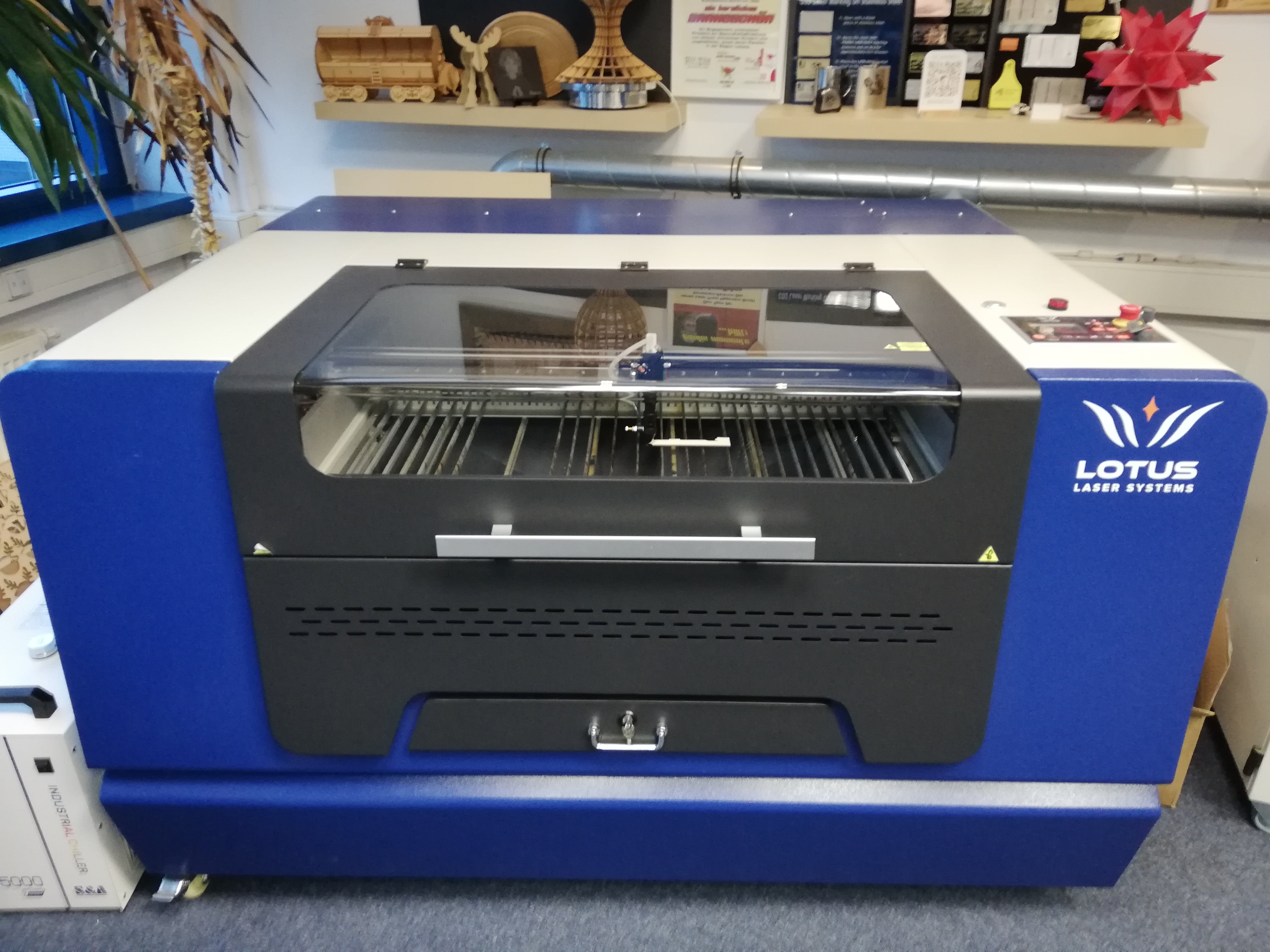 Lotus Blu 100 Maschine in blau und weiß mit schneidbrett, Glashaube, Not-Aus Knopf, Bedienungsmenu und Rollen am Boden.