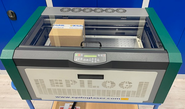 Epilog Mini 24 Maschine in Grün, Schwarz und Weiß mit Schneidtisch, Glasdeckel, Lüftern und Einstellungsmenu.