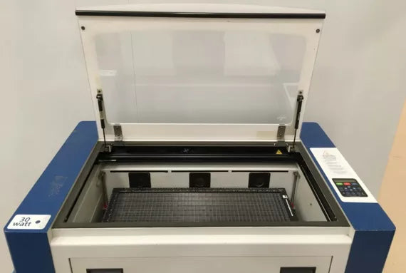 Geöffnete Epilog Zing 24 Maschine in blau und weiß mit Schneidbrett, Glashaube und Touchscreen.